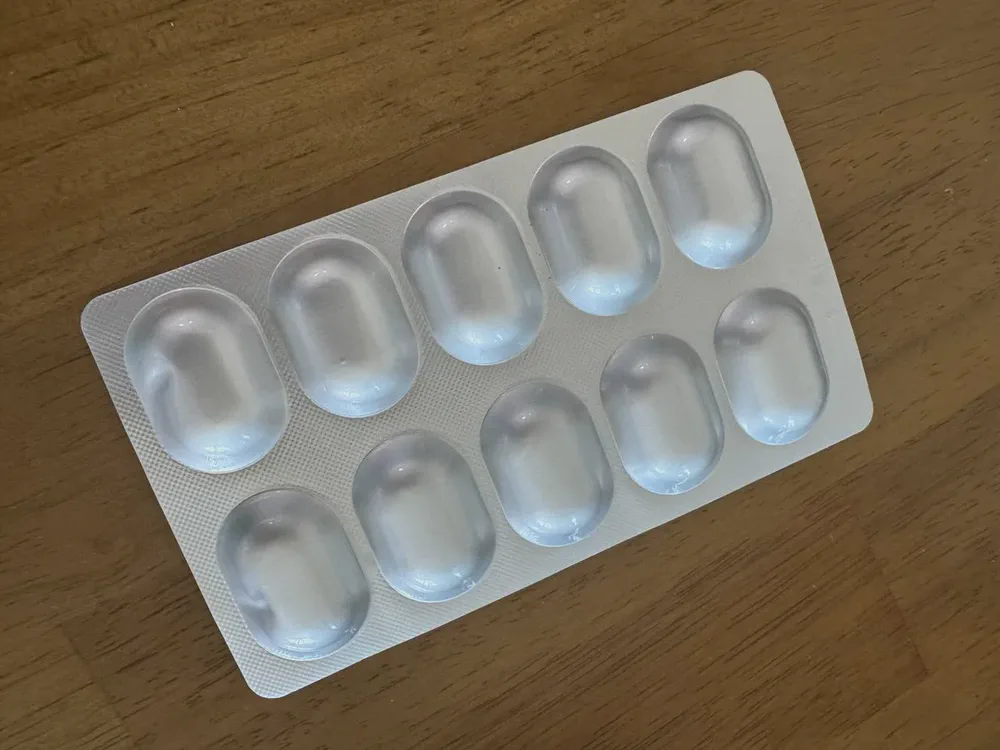 락토비프 유산균이 낱개로 밀봉된 은박 블리스터 시트. 열 칸짜리 한 판이 나무 책상 위에 놓여 있다